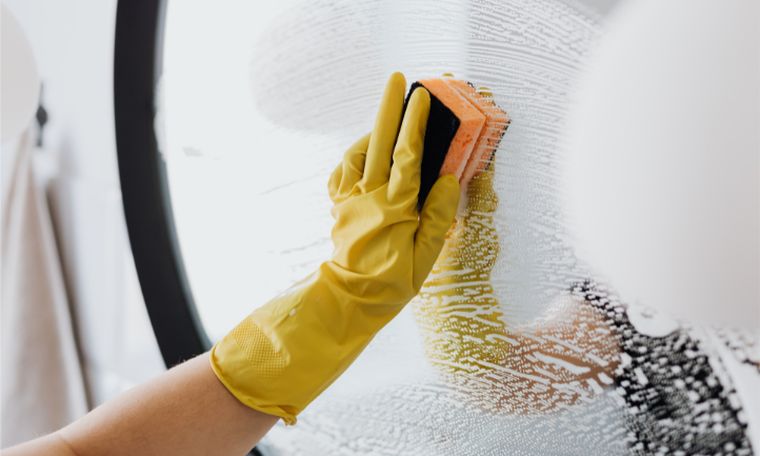 Gloved hand wiping a bathroom mirror