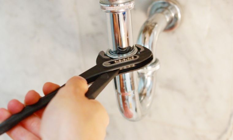 Plumber tightening a sink trap with a wrench